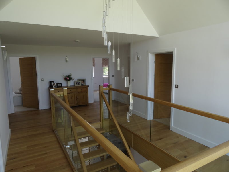 Stair Atrium of family home in York with feature chandalier and hardwood staircase with glass panels